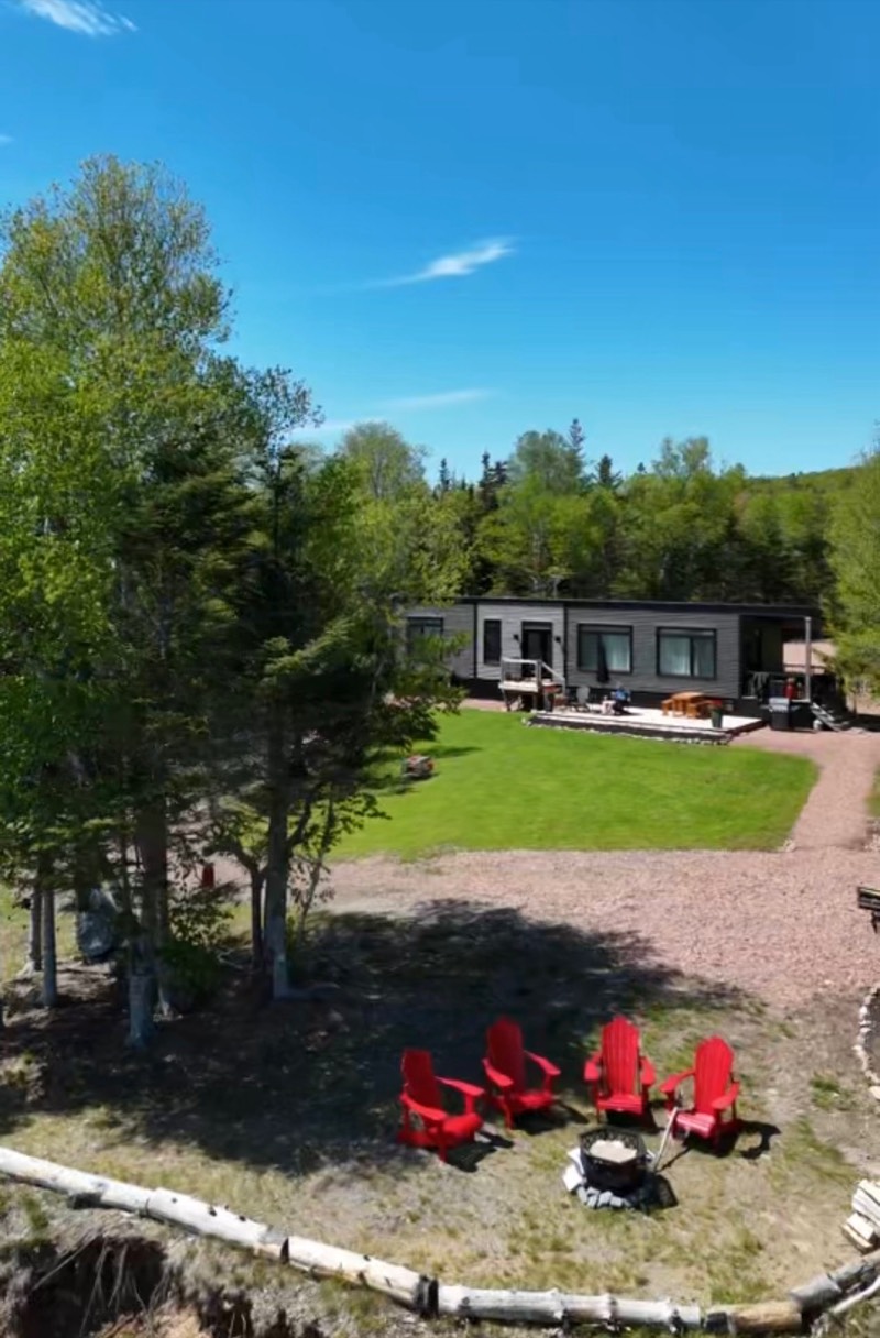 Aerial view of the cottage, its lawn and the fire pit with four red Adirondack chairs