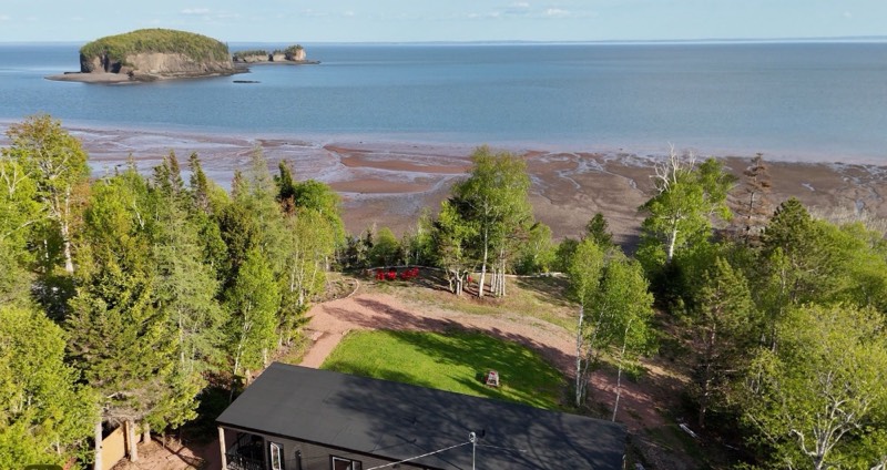 Aerial view of Tides and Trails Cottage with the Bay of Fundy sea floor exposed at low tide and the Two Islands offshore