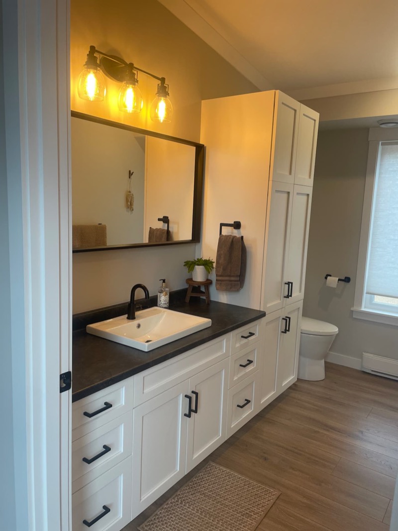 Bathroom with a long white vanity, dark countertop and warm vintage-style lights