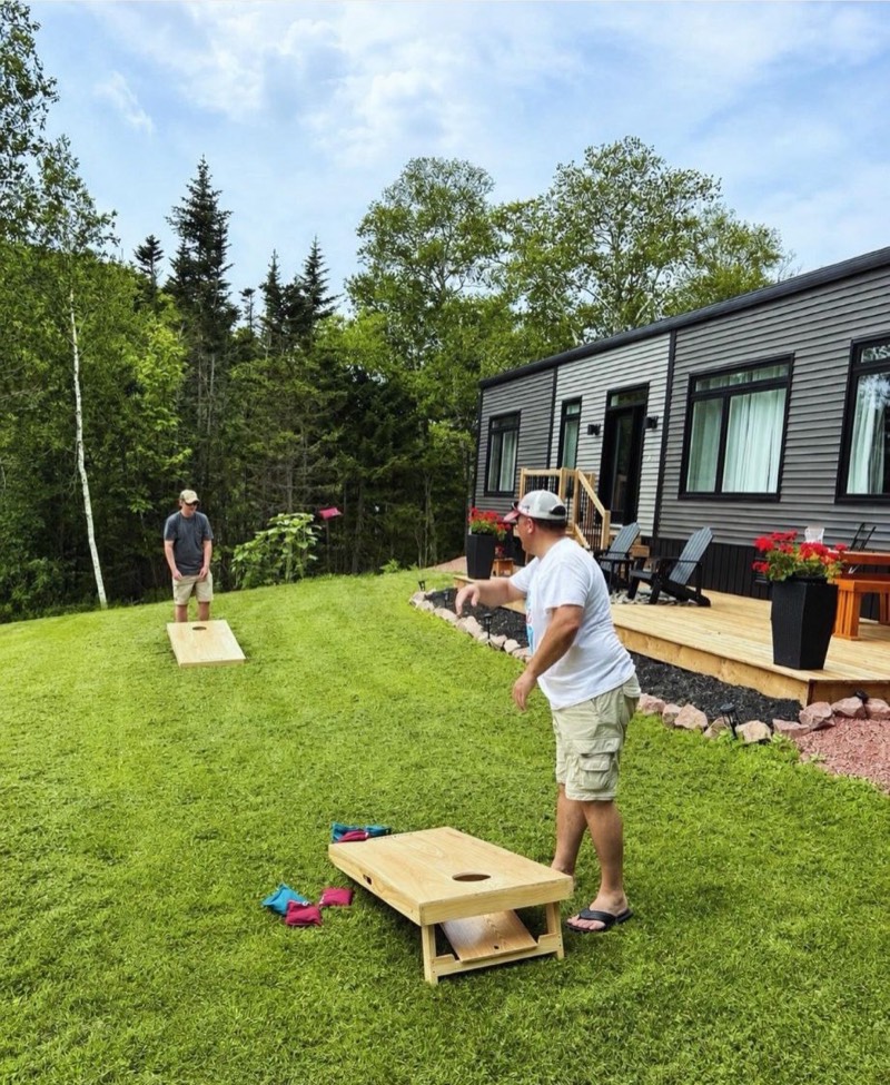 Guests playing cornhole on the lawn beside Tides and Trails Cottage