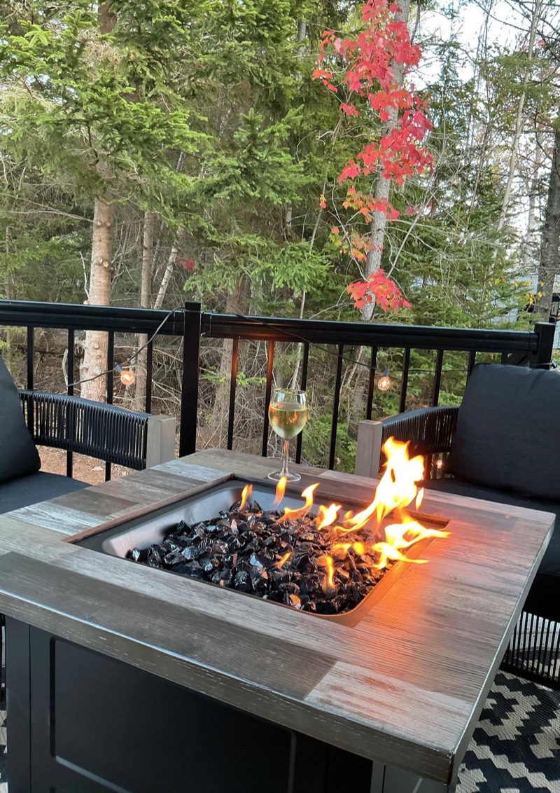 Propane fire table and a glass of wine on the covered deck in autumn