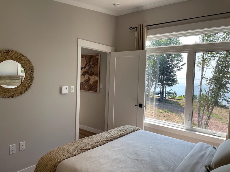 Queen bedroom with a large window looking through the trees to the Bay of Fundy